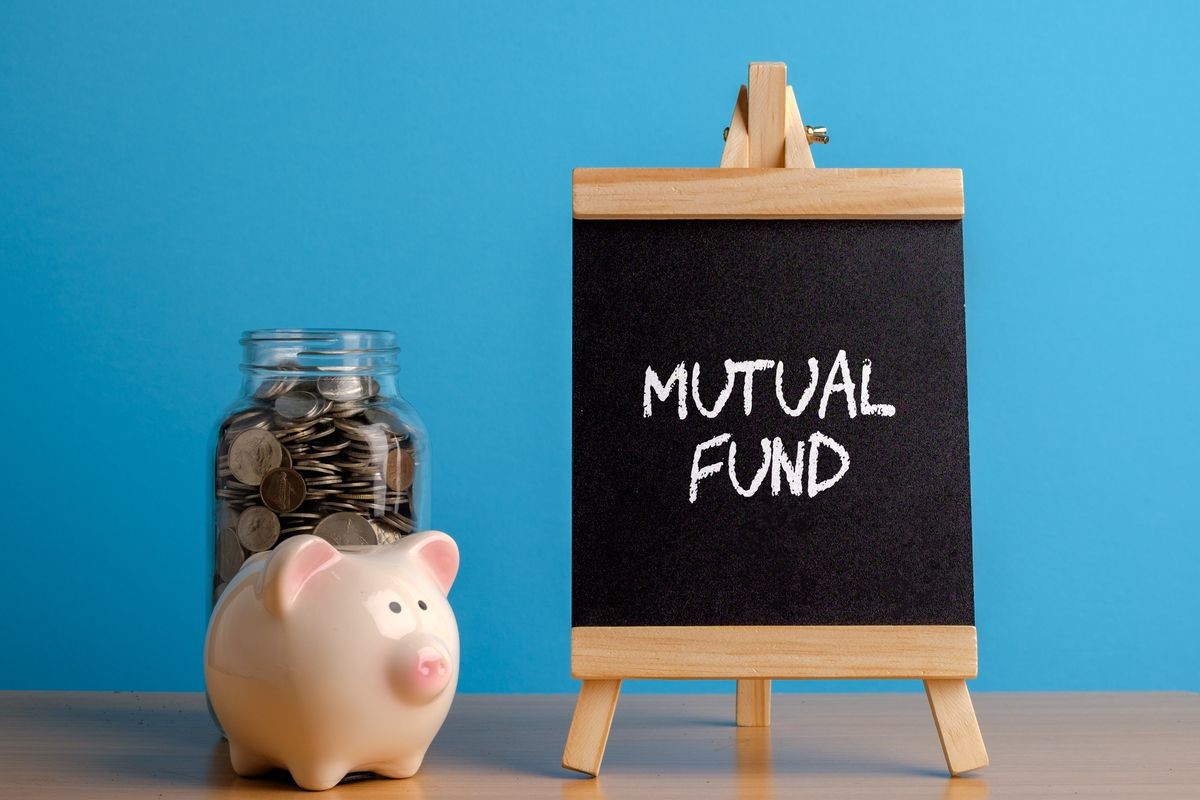 Mutual Fund, financial concept. Mason jar with coins inside, piggy bank and chalkboard on wooden table.
